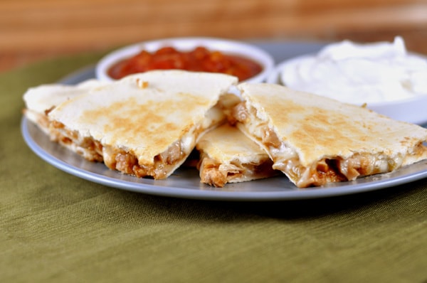 Triangle pieces of cooked chicken quesadilla on a gray plate.