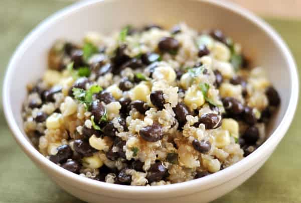 White bowl with black beans, quinoa, and corn.