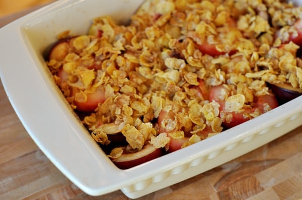 White casserole dish with roasted fruit and a crunchy topping.