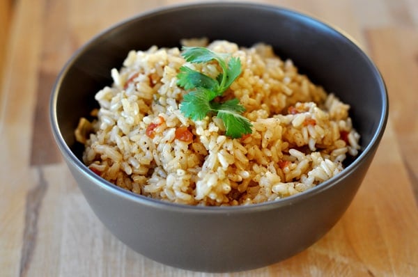 Brown bowl with baked Spanish rice topped with chopped cilantro.