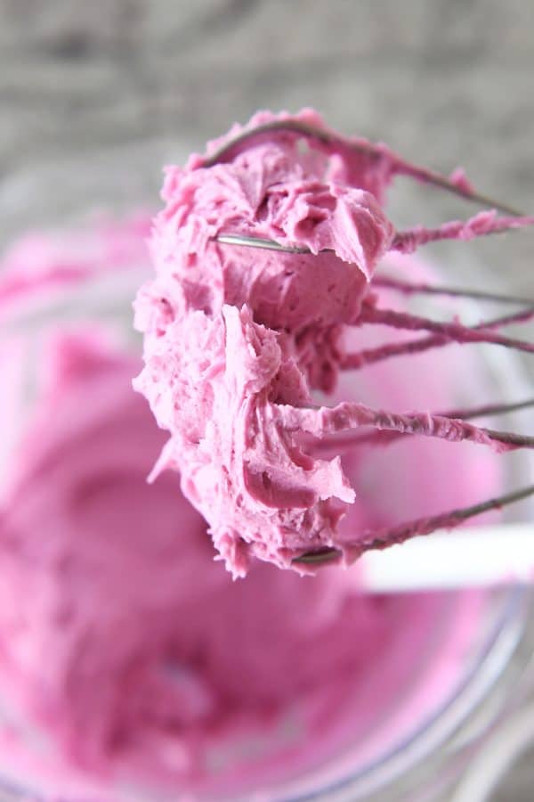 pink frosting on beaters over a bowl of more frosting