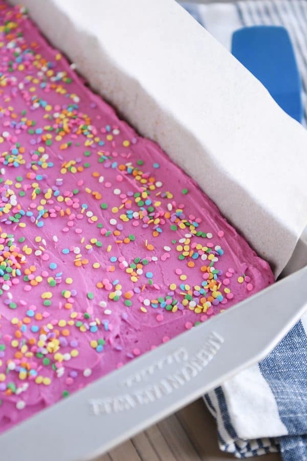 Pan of sugar cookie bars with pink frosting and sprinkles.