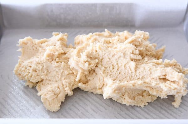 Dough for easy sugar cookie bars being piled in metal pan.