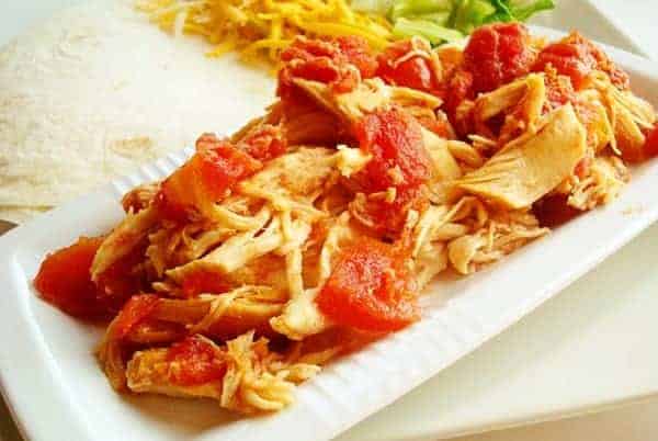 White rectangular platter with shredded chicken and diced tomatoes.
