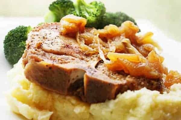 Cooked bone-in pork chop on top of mashed potatoes.