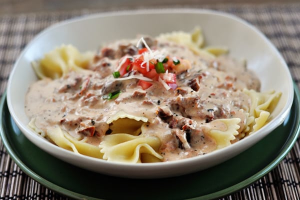white dish with cooked bowtie pasta covered in a creamy tuscan sauce