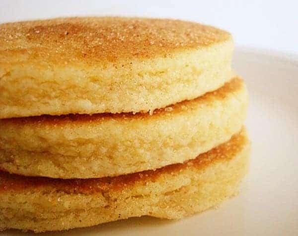 Stack of three thick pancakes on a white plate.