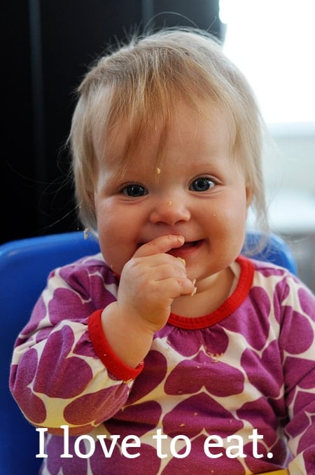 a baby girl eating with food on her face