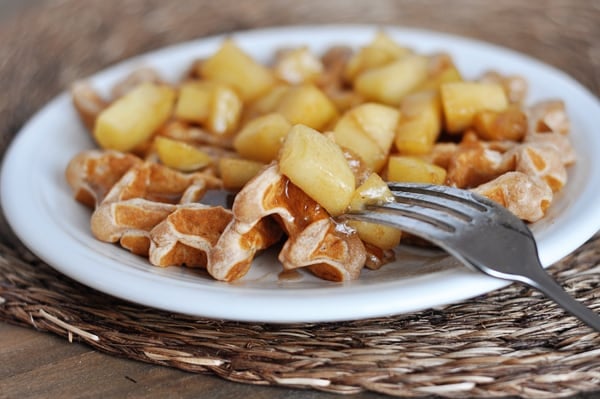 Apple cinnamon covered waffle on a white plate.