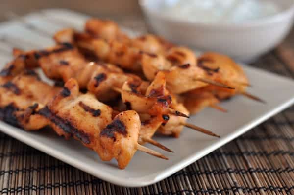 White platter with grilled chicken skewers.