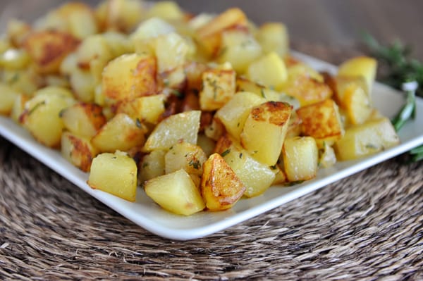 Golden brown cooked potato cubes on a white platter.