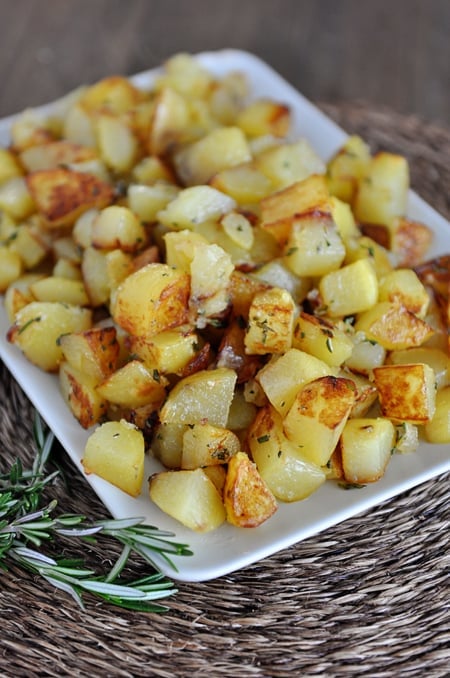 A white dish with golden brown cooked potato cubes.