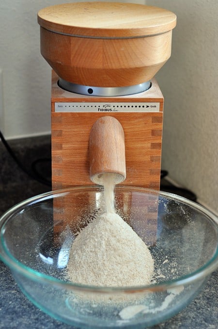 a wheat grinder grinding wheat into a glass bowl