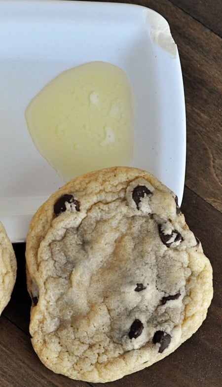 top view of a flattened chocolate chip cookie and melted butter 