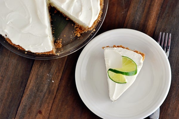 Top view of a slice of sour cream lime tart on a white plate with a slice of lime on top.
