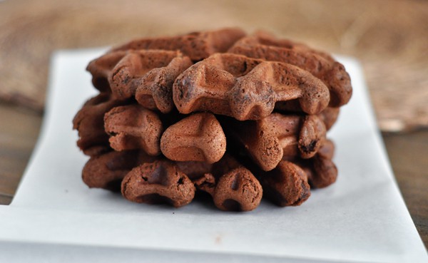 Three chocolate waffle cookies stacked on top of each other on a piece of parchment.