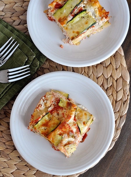 Top view of two white plates with pieces of zucchini lasagna on them.