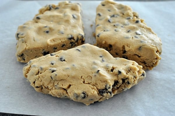 three chunks of chocolate chip cookie dough on a piece of parchment