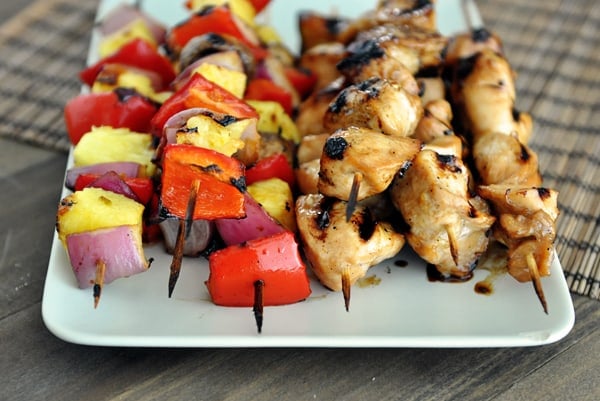 a white platter with grilled veggie kebabs on the left and grilled chicken kebabs on the right