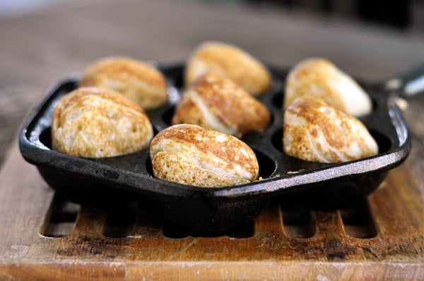 Side view of seven golden brown cooked ebelskiver's in an ebelskiver pan.