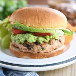 jalapeno cheddar turkey burger with guacamole, tomato, and lettuce on white plate