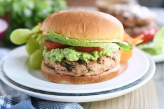 jalapeno cheddar turkey burger with guacamole, tomato, and lettuce on white plate