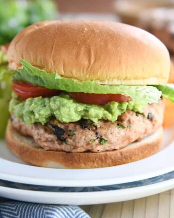 jalapeno cheddar turkey burger with guacamole, tomato, and lettuce on white plate