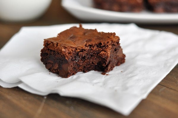 A brownie with a bite taken out of it sitting on a napkin.