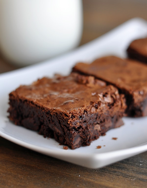 Brownie squares lined up on a white platter.