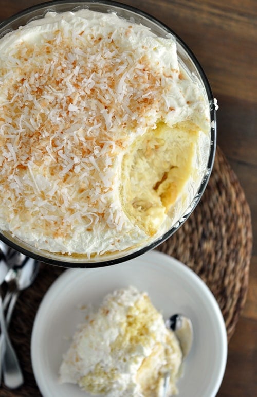 Top view of a trifle dish full of coconut-topped tres leches with a scoop taken out.