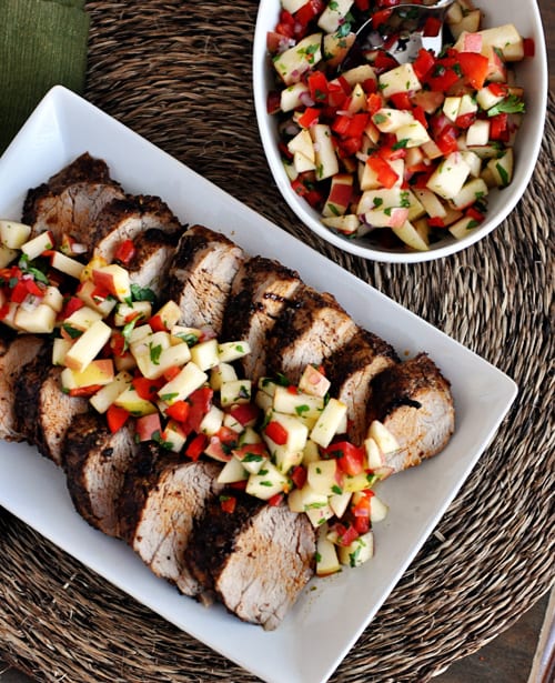 Top view of grilled pork loin slices with a fresh apple salsa on top.