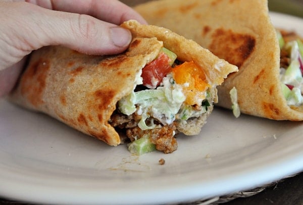 Greek flatbread taco with a bite taken out on a white plate.