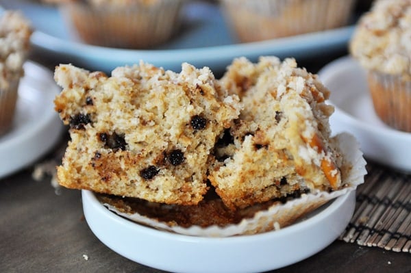 A pretzel chocolate chip muffin split in half on a small white plate.