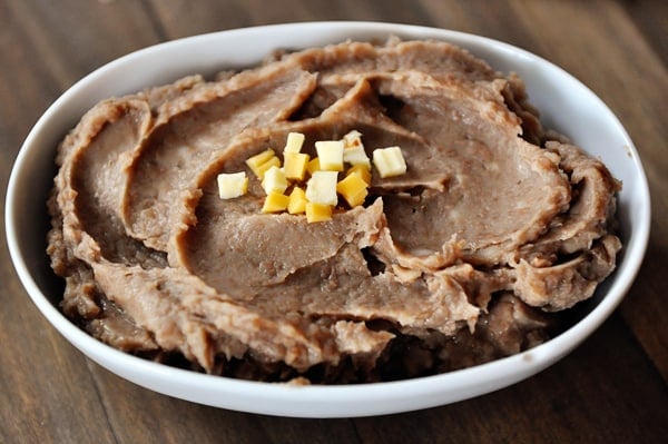 White oval bowl full of refried beans.