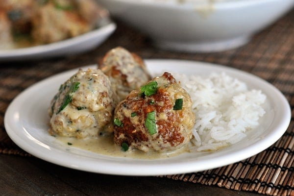 Three sauce-covered meatballs and cooked white rice on a plate.