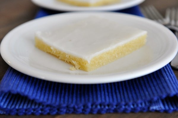 White plate with a piece of white texas sheet cake.