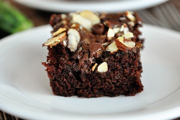 A piece of streusel-topped chocolate zucchini cake on a white plate.