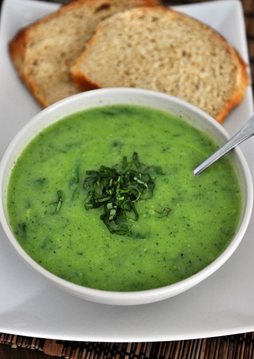 a bowl full of green soup next to two pieces of toast