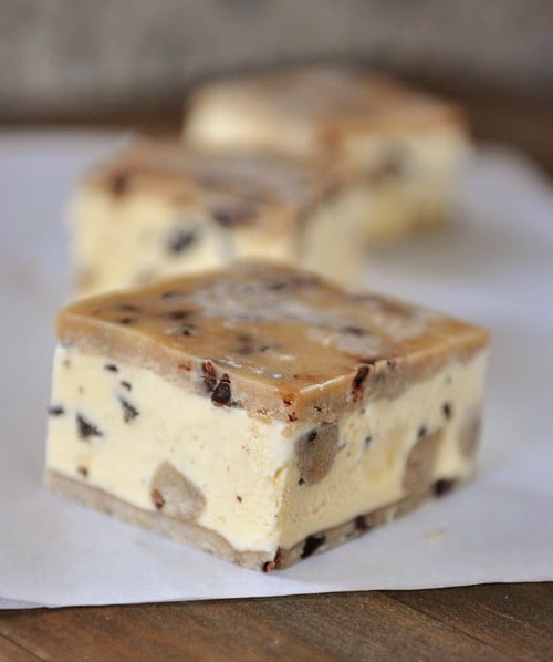 Three cookie-dough ice cream sandwiches lined up on a piece of parchment paper. 