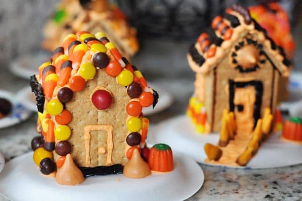 Halloween-theme decorated graham cracker houses on white plates