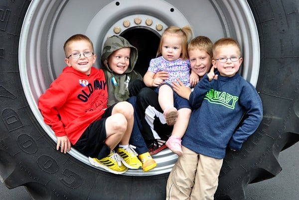 five little kids sitting inside the rim of a giant tire