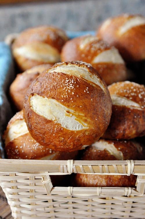 A basket full of salted golden brown pretzel rolls.