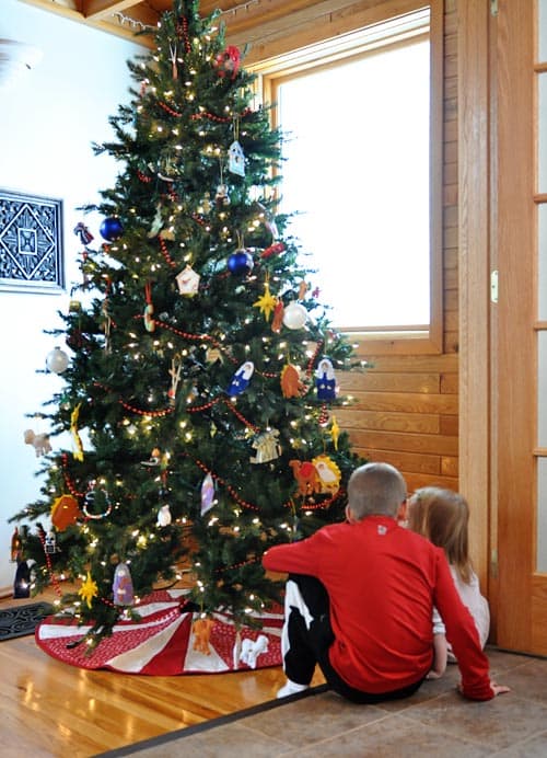 little kids sitting by a decorated Christmas tree