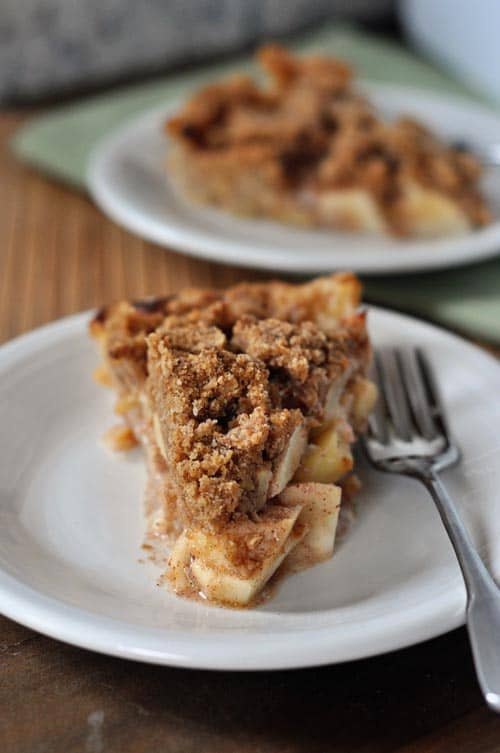 two slices of apple crumb pie on white plates