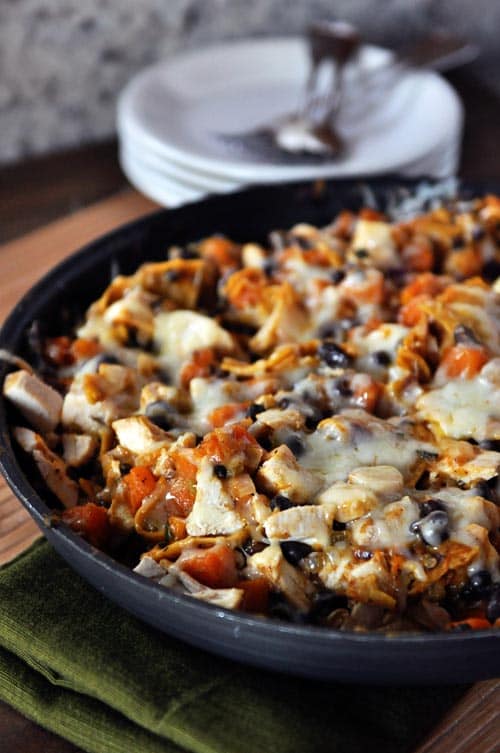 A cast iron skillet full of a cheesy black bean enchilada dinner.