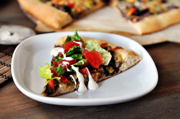 A slice of black bean taco pizza on a white plate.