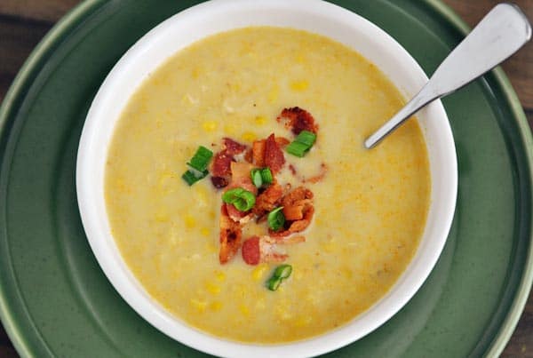 top view of white bowl full of corn chowder topped with sliced green onions and chopped bacon