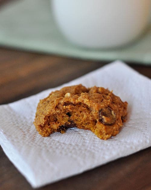 A chocolate chip pumpkin oat cookie with a bite taken out on a napkin.