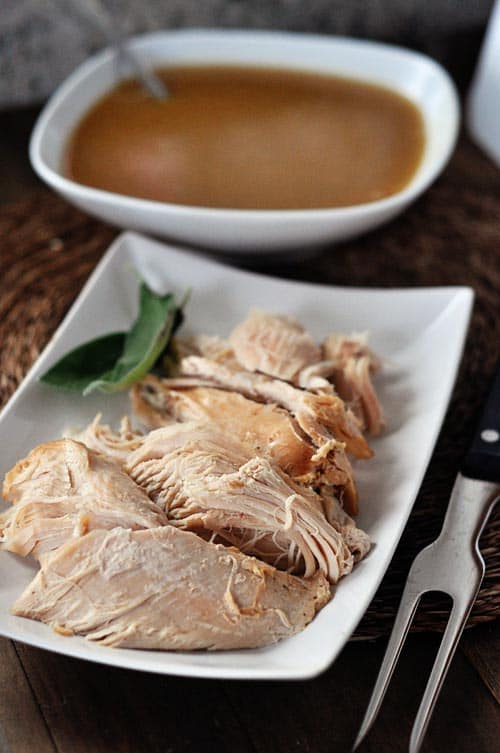 Pieces of cooked turkey breast with gravy on top on a white platter.