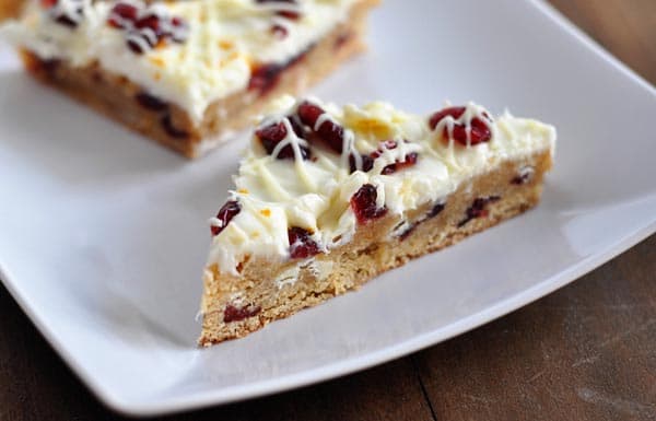 cranberry bliss bars cut into triangle shapes on a white platter